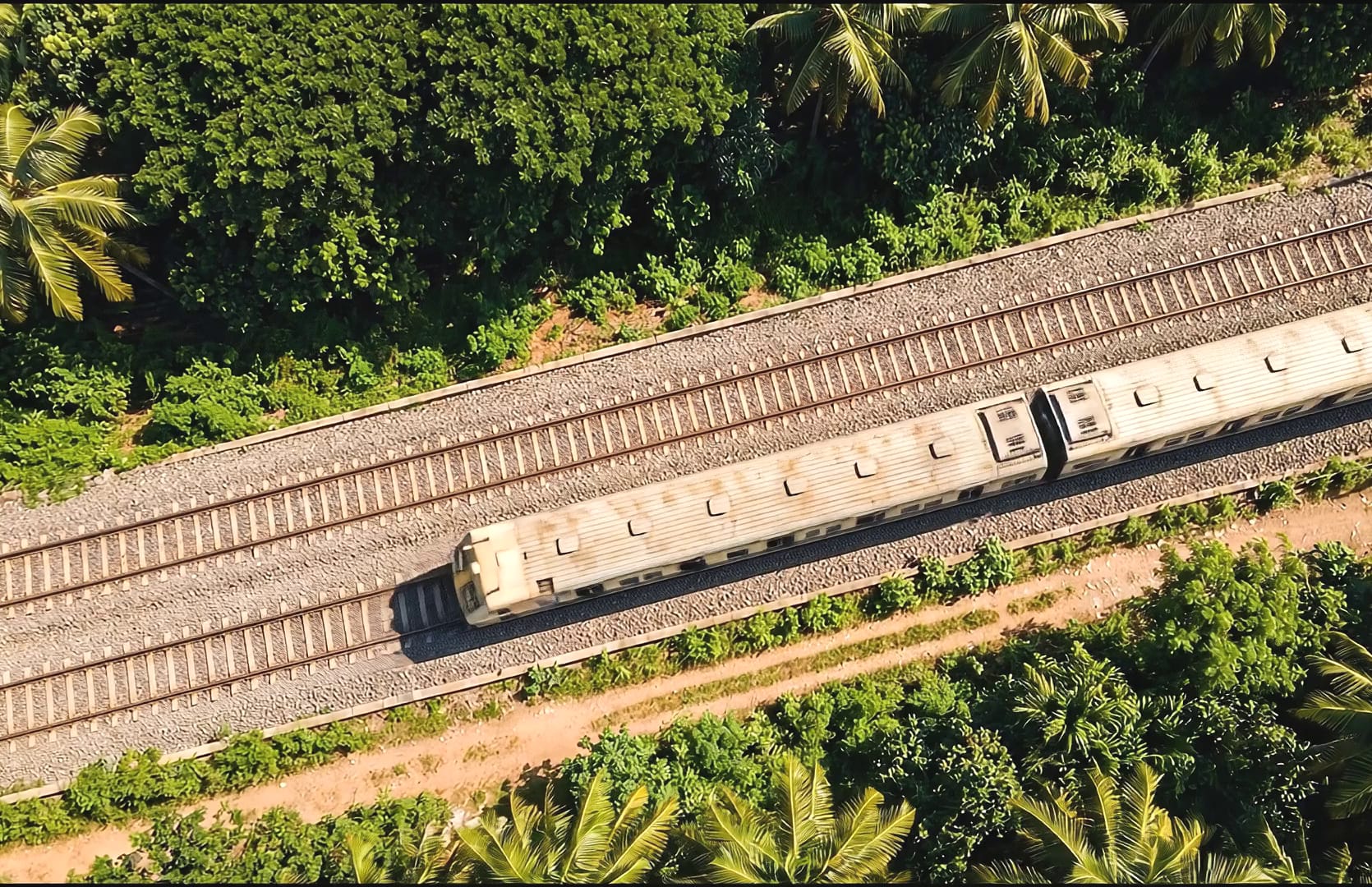 A double-track railway line carrying a commuter train, seen from directly overhead